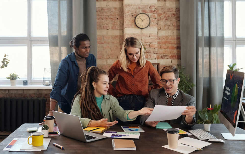 How To Craft A Marketing Strategy That Can Boost Sales - Marketing Team Sitting At A Table With Papers