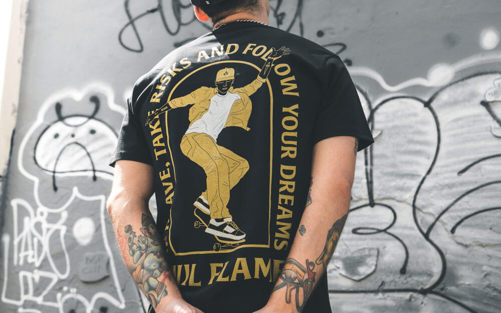 Man wearing a Custom Merch Design On A T-Shirt, standing in front of a graffiti wall
