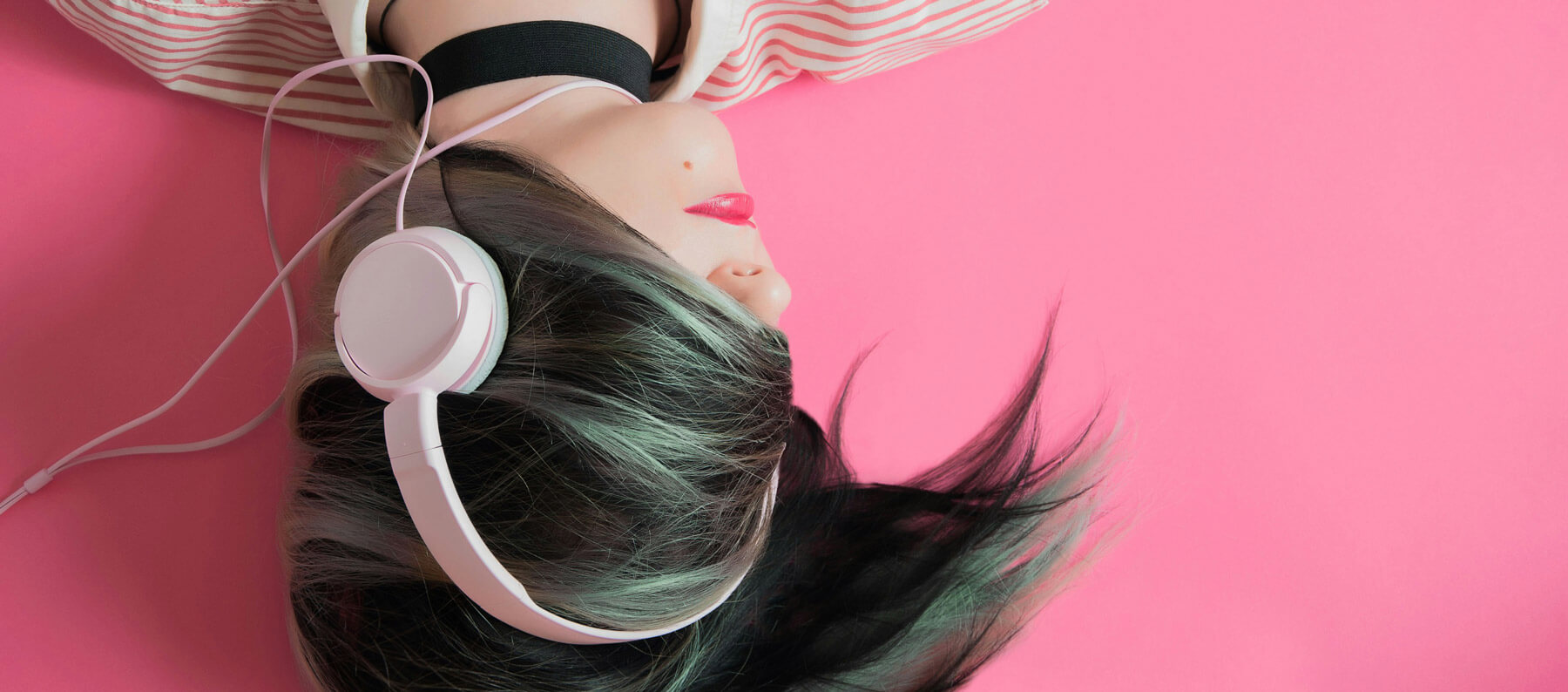 Music industry trends - showing a music brand image of a woman with headphones laying on a pink background
