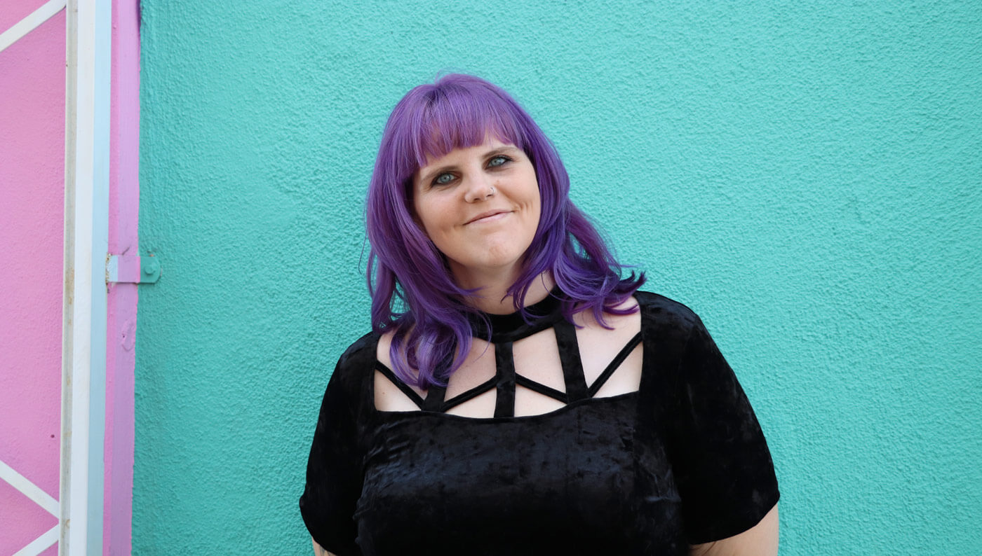 Website Design and Branding Designer, Megan Gersch, standing in front of a teal wall